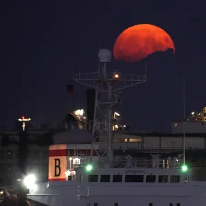 Der Vollmond geht am Abend über den Hamburger Hafen auf.