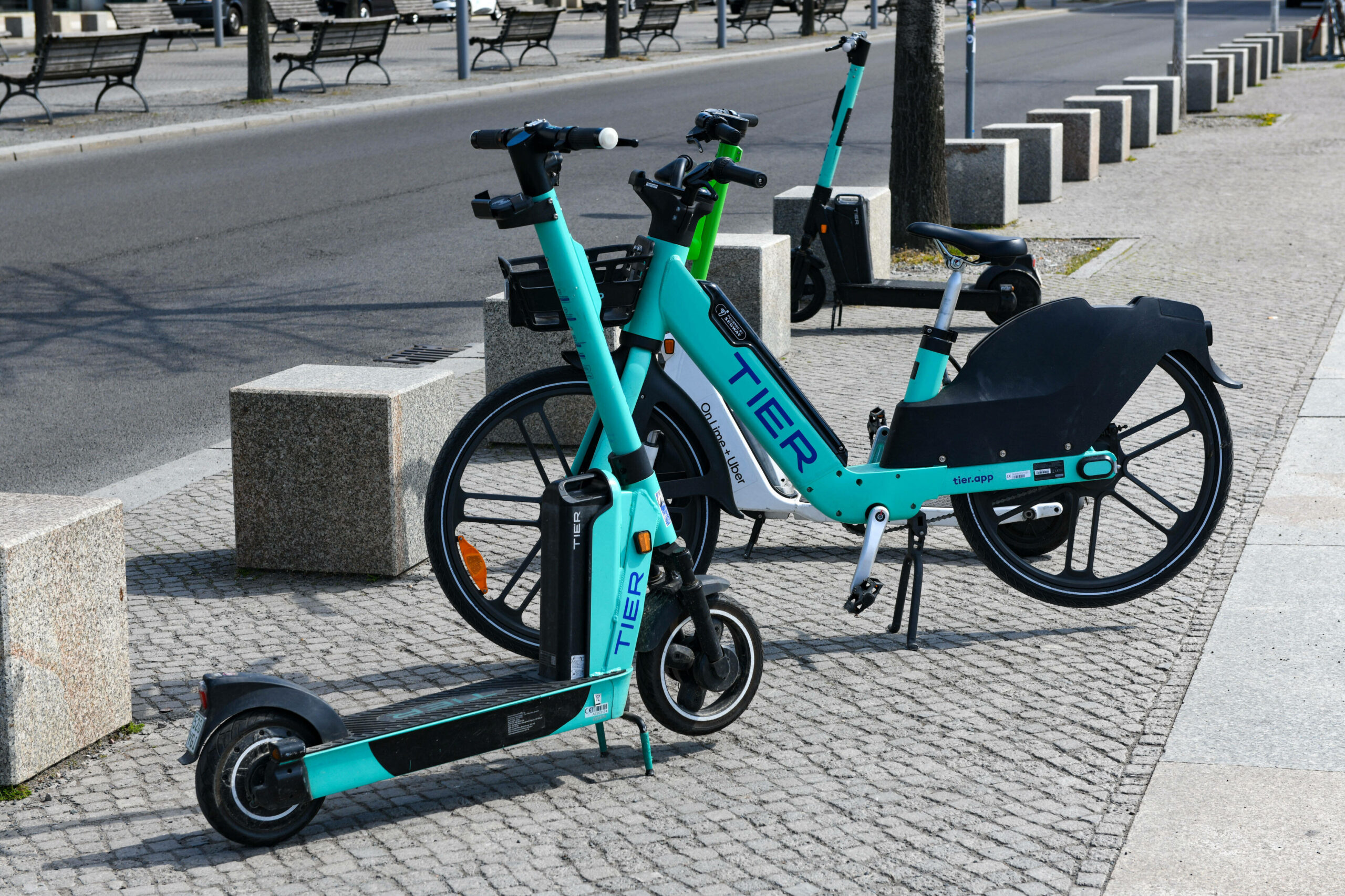 Ein eScooter und E-Bike der Firma Tier stehen in Berlin an einer Straße zum mieten.