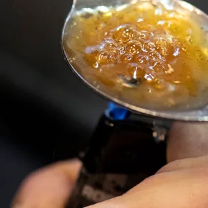 Über der Flamme eines Feuerzeuges kocht eine Person eine Portion Heroin in einem Löffel auf. (Symbolbild)