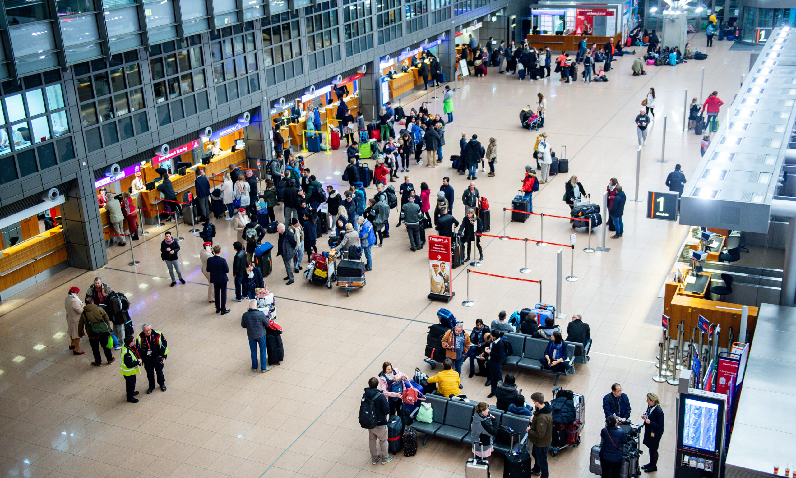 Fluggäste warten in der Abflughalle des Hamburger Flughafens vor einem Ticketschalter. Die Gewerkschaft Verdi hat zum Warnstreik aufgerufen. (Archivfoto)