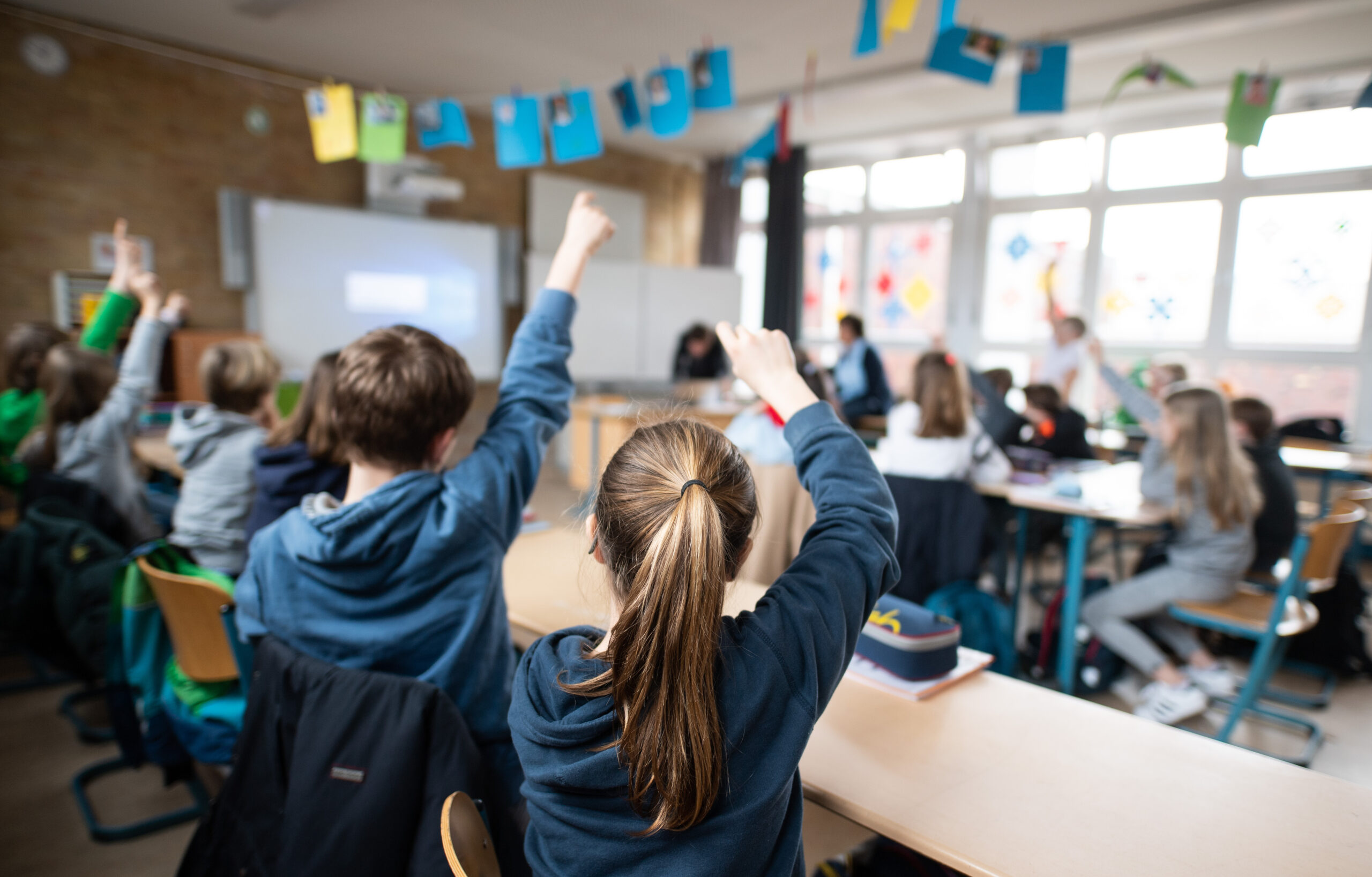 Symbolbild: Schüler einer fünften Klasse eines Gymnasiums melden sich im Unterricht. Vorn im Klassenzimmer hängt ein Smartboard.