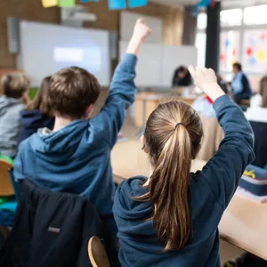 Symbolbild: Schüler einer fünften Klasse eines Gymnasiums melden sich im Unterricht. Vorn im Klassenzimmer hängt ein Smartboard.