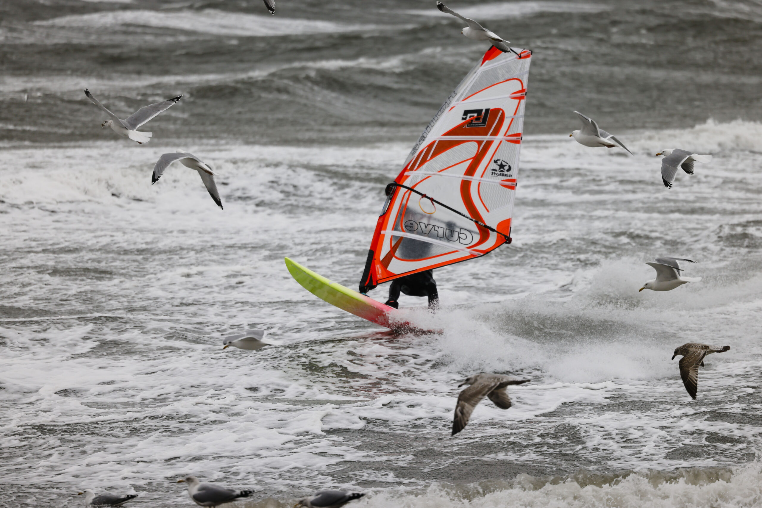 Ein Windsurfer gleitet bei stürmischen Wetter auf der Ostsee.