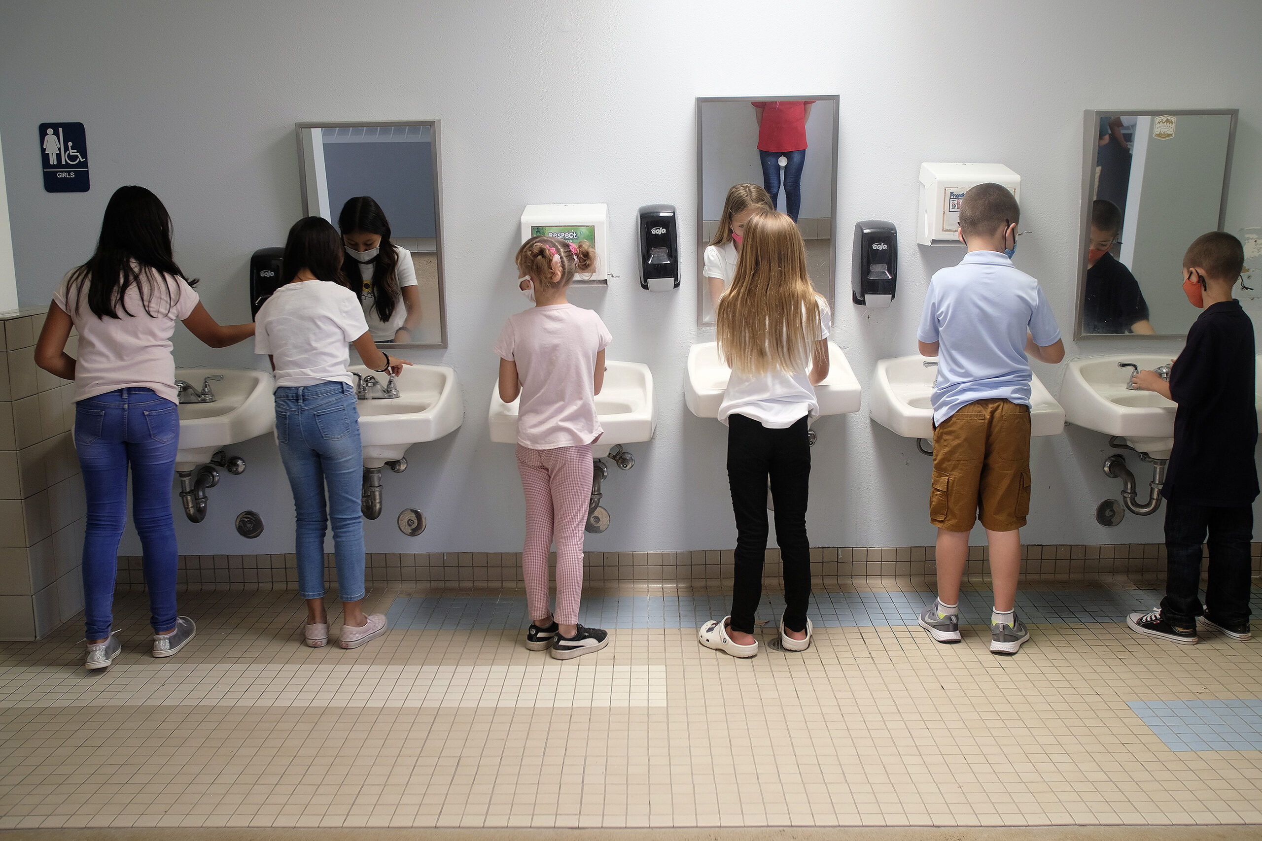 Kinder waschen sich die Hände in einem öffentlichen Waschbecken.