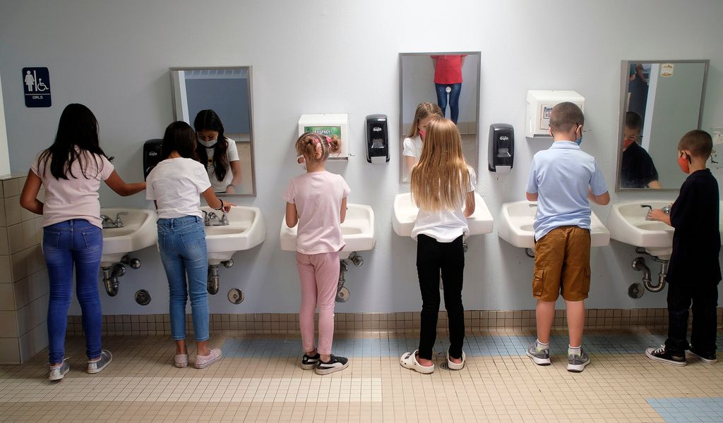 Kinder waschen sich die Hände in einem öffentlichen Waschbecken.