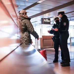 Zwei Beamte der Bundespolizei kontrollieren am Flughafen einen Mann (Symbolbild).