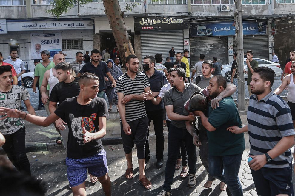 Eine Gruppe Männer hilft einer verletzten Person nach einem israelischen Luftangriff.