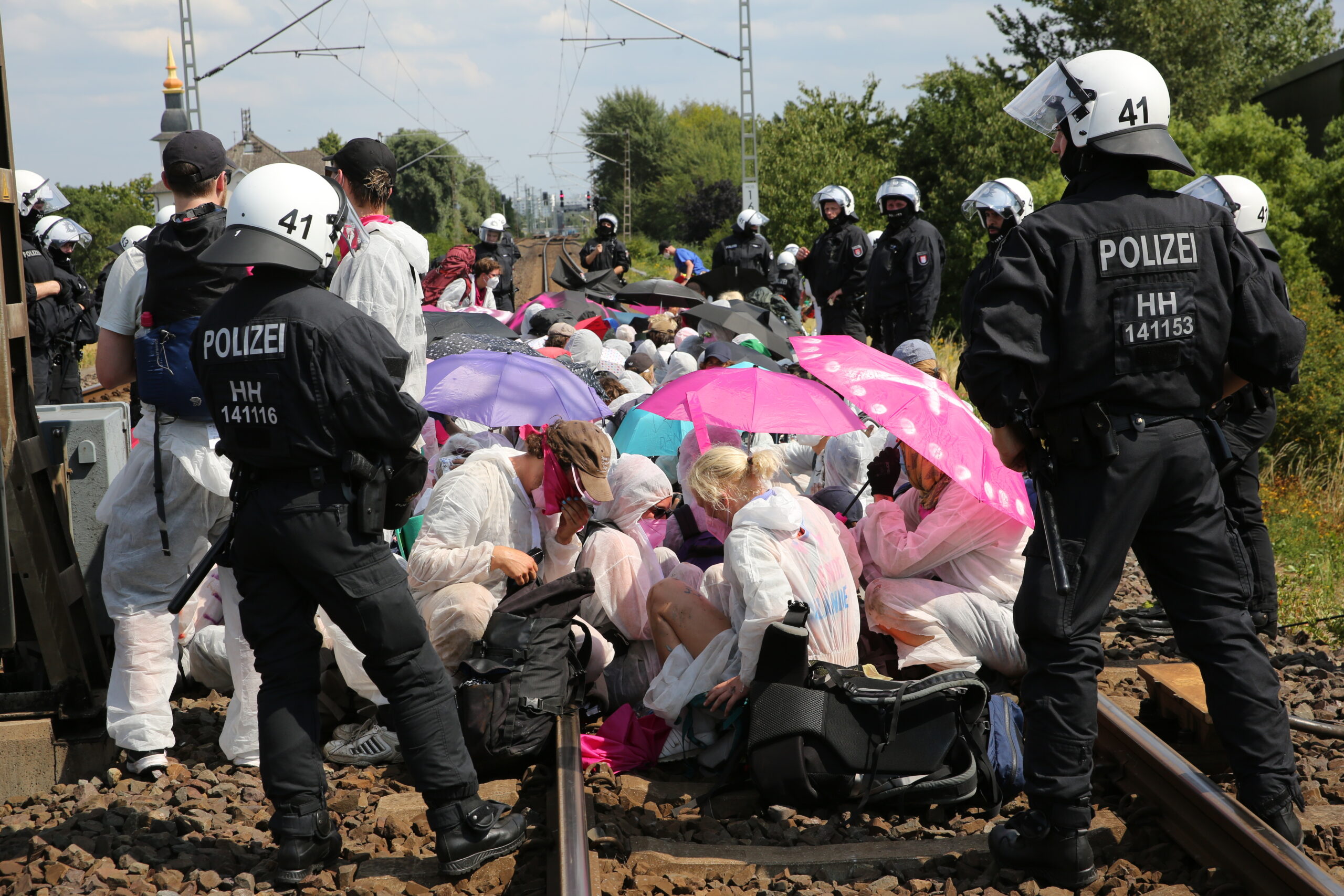 Klimaaktivisten und Teilnehmer des Klimacamps sitzen am Samstag umringt von Polizei bei einem Protest auf Gleisen in Hamburg-Wilhelmsburg.