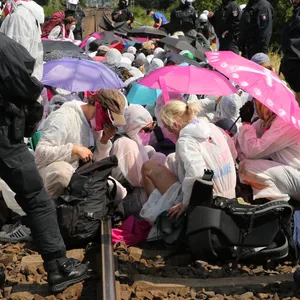 Klimaaktivisten und Teilnehmer des Klimacamps sitzen am Samstag umringt von Polizei bei einem Protest auf Gleisen in Hamburg-Wilhelmsburg.