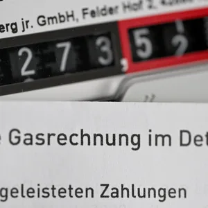 Eine Gasrechnung wird vor einen Gaszähler in einem privaten Haushalt gehalten. (Symbolbild)