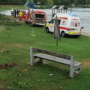 Rettungsfahrzeuge stehen neben umgekippten Bäumen an einer Unfallstelle am St. Andräer See. Bei einem schweren Unwetter, bei dem mehrere Bäume umgekippt sind, sind zwei Kinder gestorben und weitere Personen wurden teils schwer verletzt.