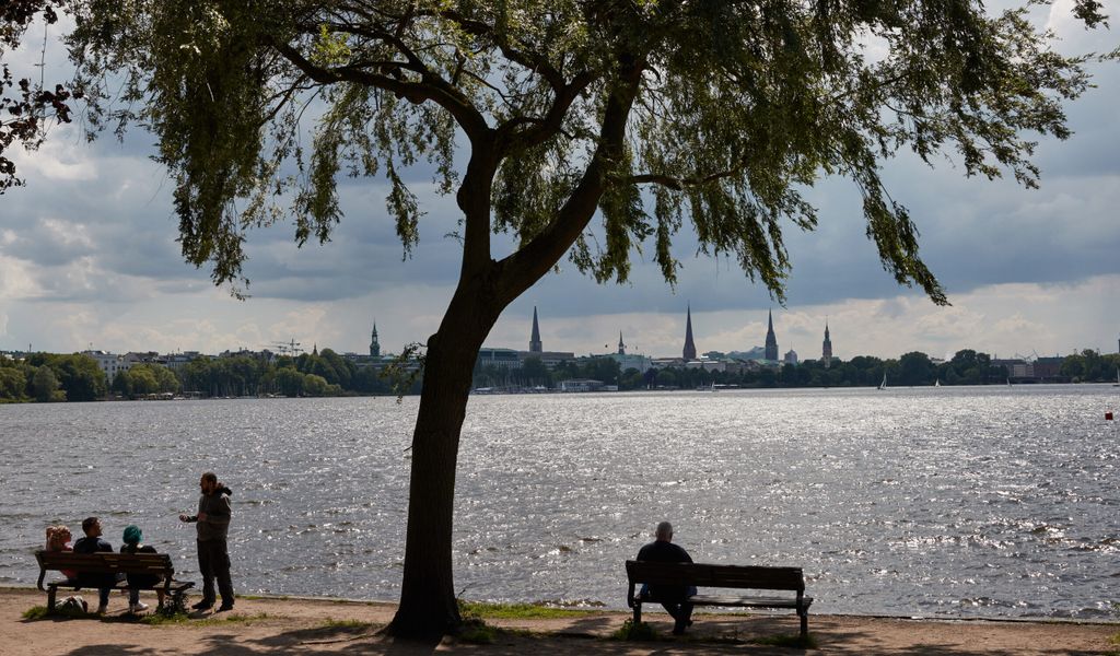 Menschen sitzen und stehen am Ufer der Außenalster. Die CDU in der Hamburgischen Bürgerschaft setzt sich für mehr Klönbänke in der Stadt ein.