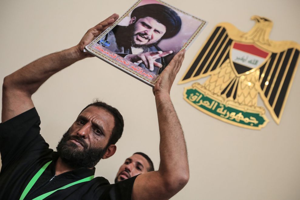 Ein Anhänger des schiitischen Geistlichen Al-Sadr hält ein Bild von ihm hoch.