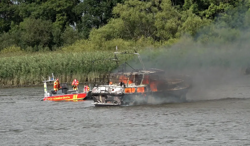 Ein Boot brennt auf dem Wasser, daneben ein Feuerwehrboot