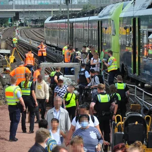 Menschen laufen neben einem Zug auf den Gleisen