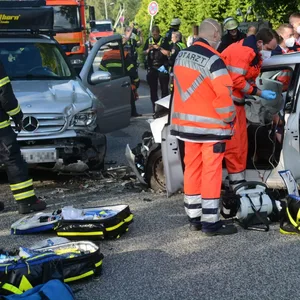 Rettungskräfte stehen neben zwei verunfallten Autos