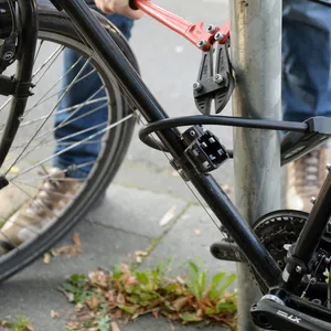 Ein Mann versucht mit einem Bolzenschneider ein Fahrradschloss aufzubrechen (gestellte Szene).