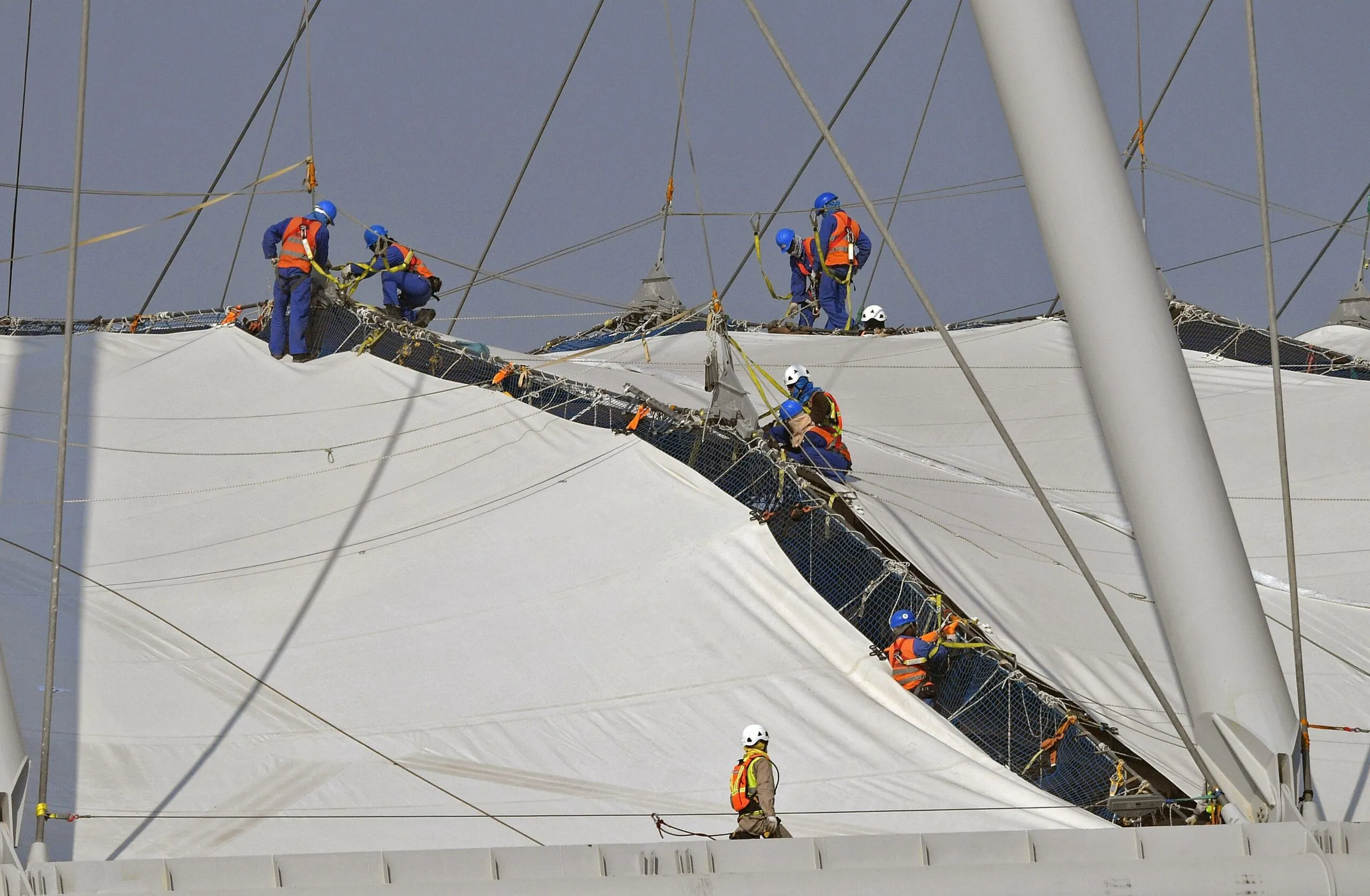 WM-Gastarbeiter in Katar auf einem Stadiondach.