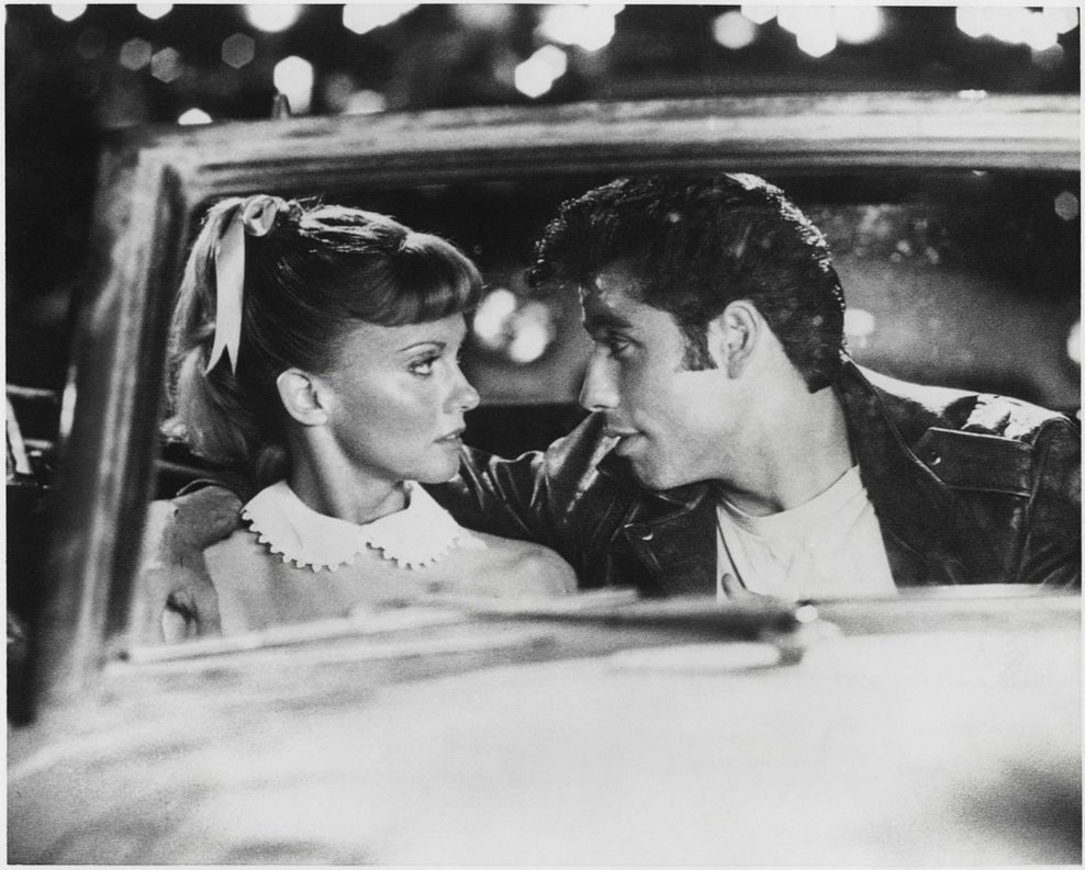 Szene aus „Grease“: Olivia Newton-John und John Travolta sitzen im Auto und schauen sich an