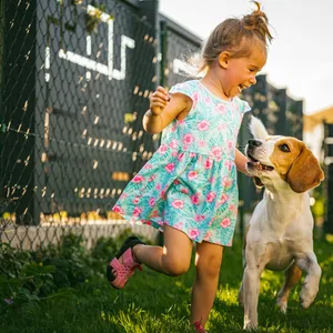 Eine neue Studie zeigt: Auch Hunde können vor Freude weinen (Symbolbild). Ein kleines Mädchen läuft lachend in einem bunten Kleid mit einem Hund durch den Garten.