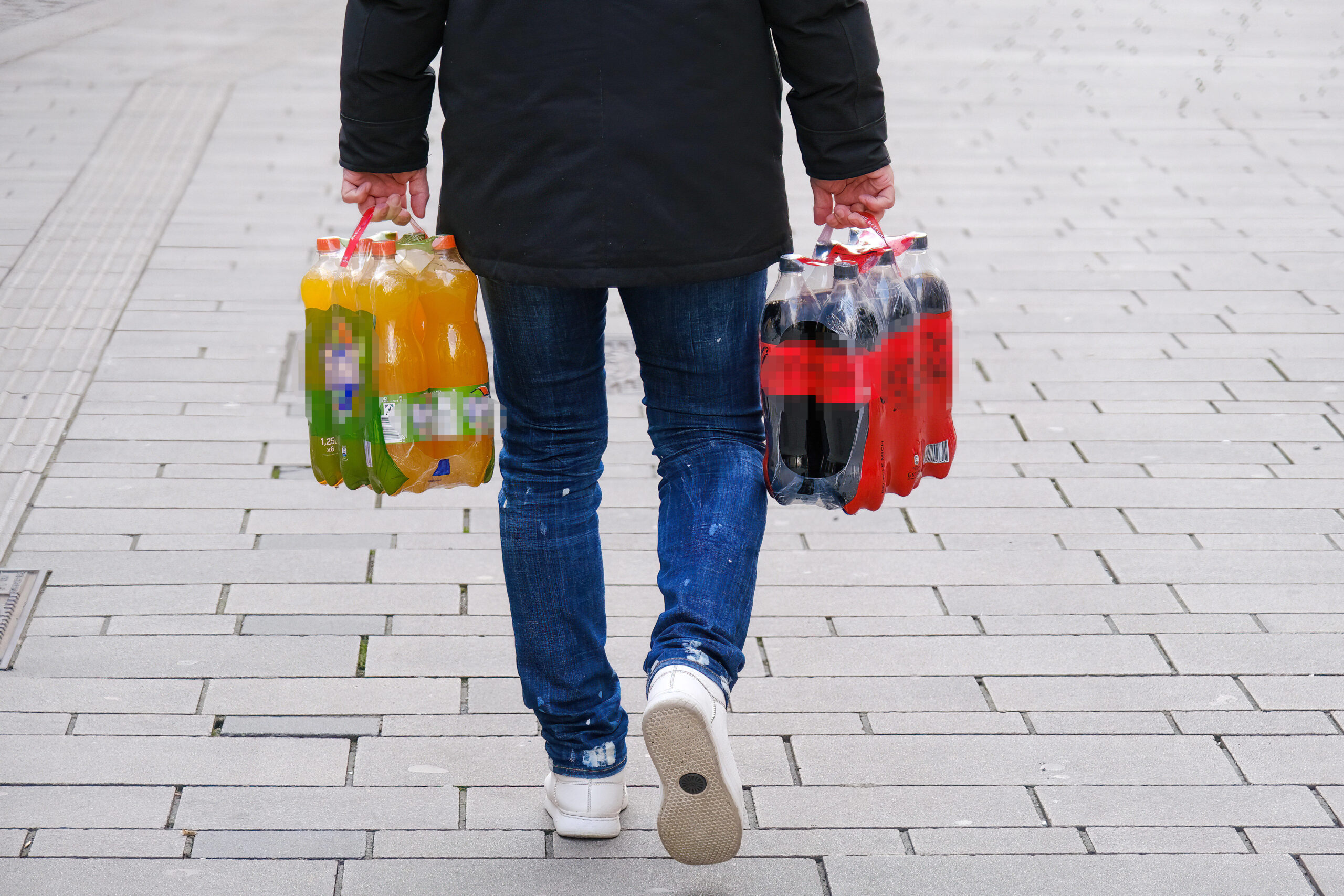 Eine Person trägt Getränkeflaschen vom Einkaufen nach Hause. (Symbolbild)