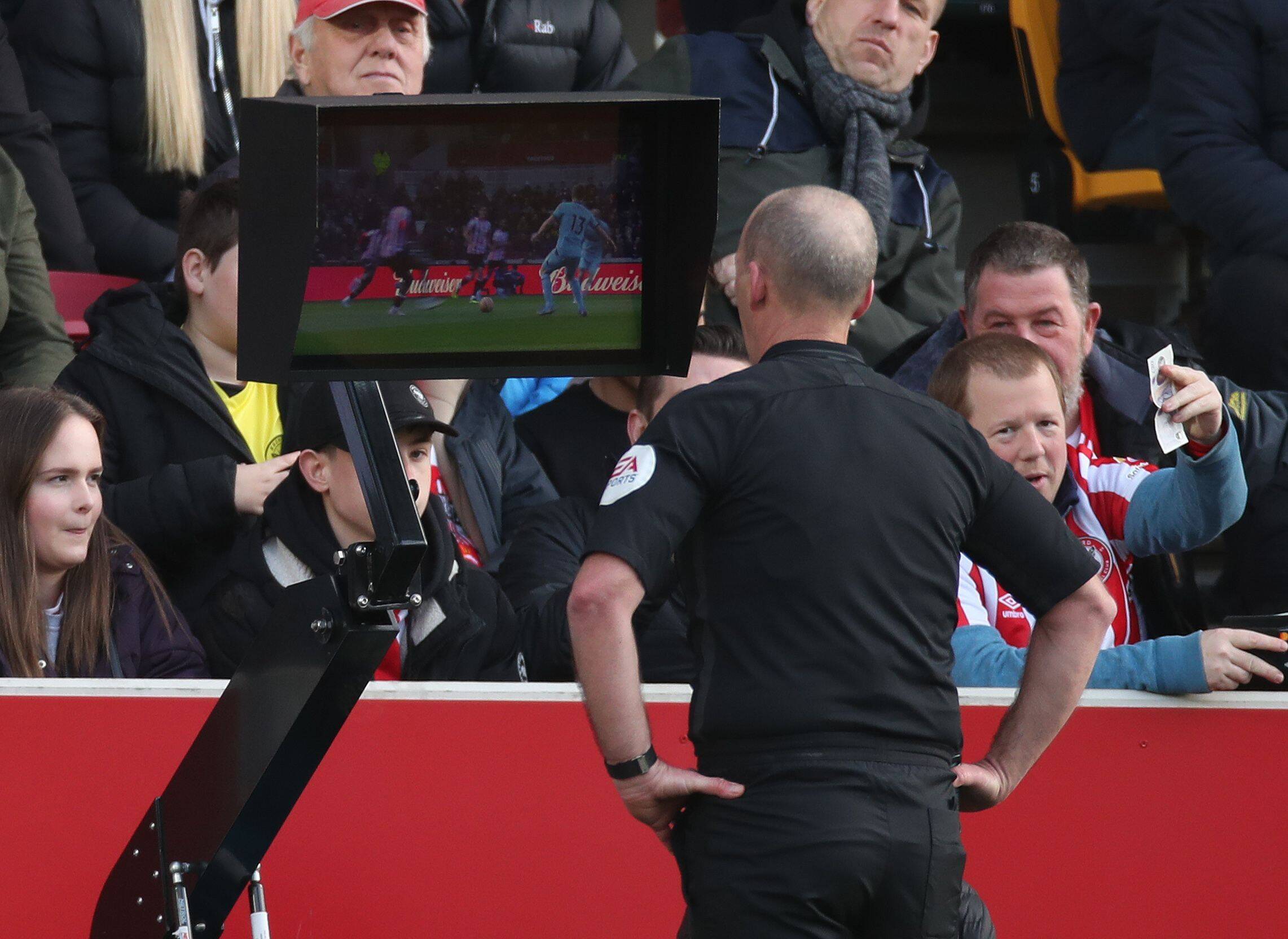 Premier-League-Schiedsrichter Mike Dean schaut sich eine Spielszene über den Videoassistenten erneut an.