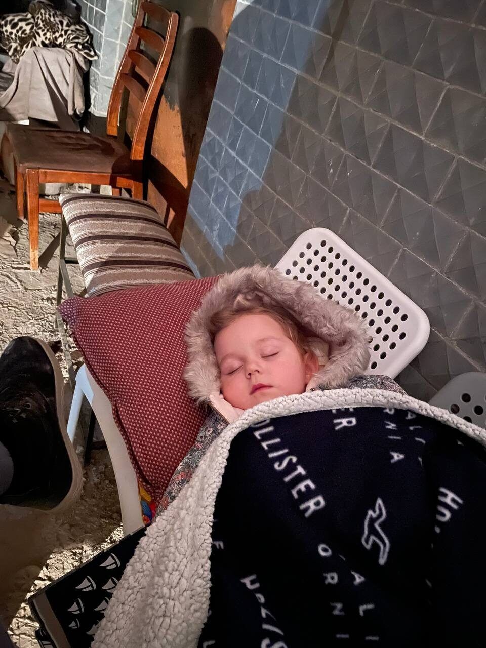 Kind schlafen auf Stühlen in einem Keller.