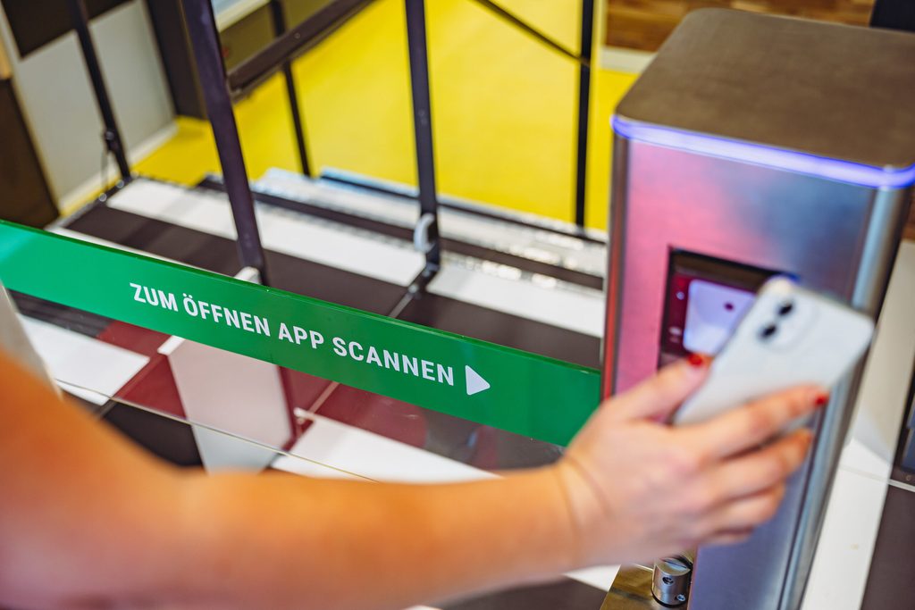 Um in den Laden zu kommen, lade ich vorab eine App auf das Handy und scanne sie am Eingang.