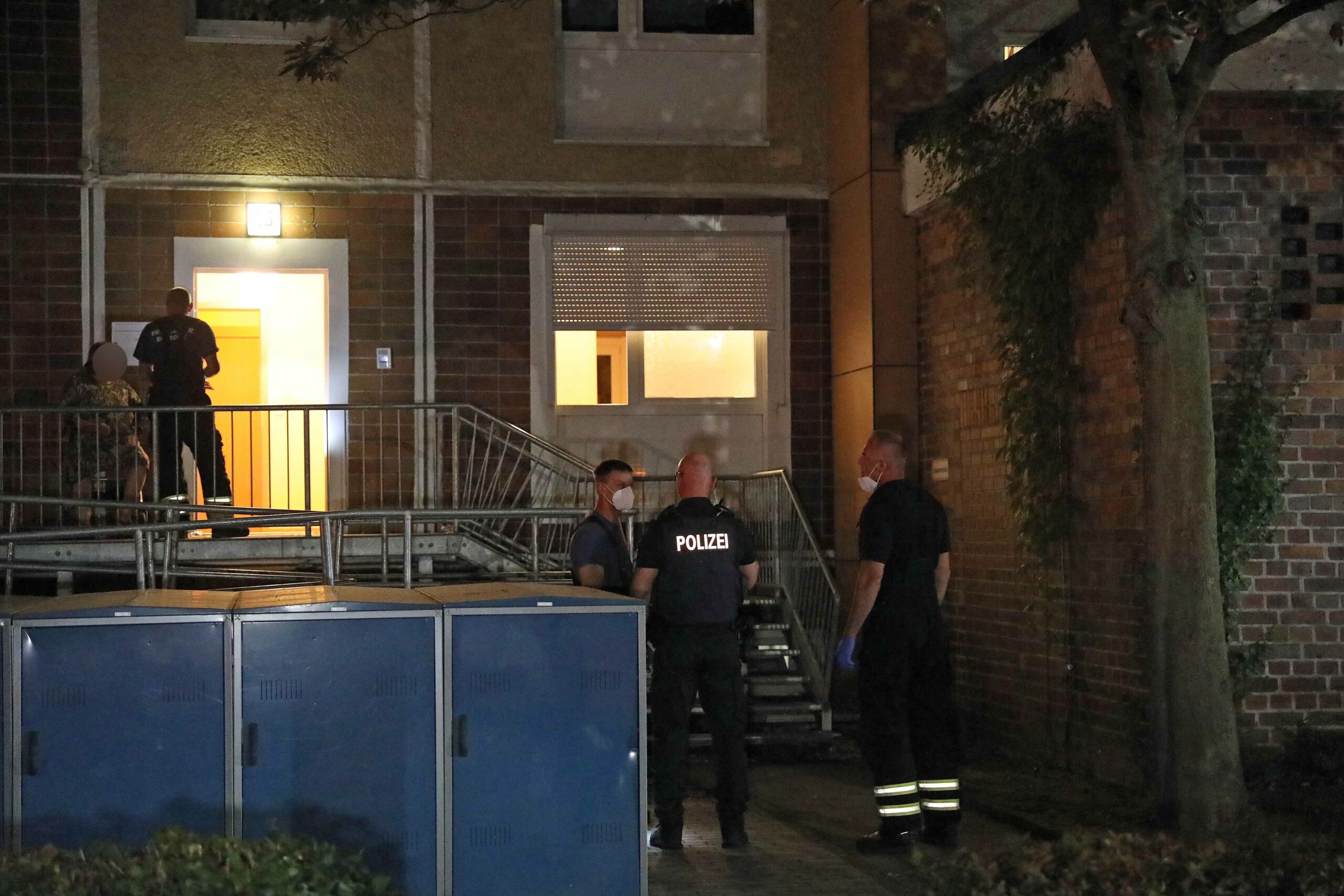 Beamte stehen vor der Wohnung des 25-Jährigen Rostockers, der am Samstagabend attackiert wurde.