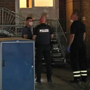 Beamte stehen vor der Wohnung des 25-Jährigen Rostockers, der am Samstagabend attackiert wurde.