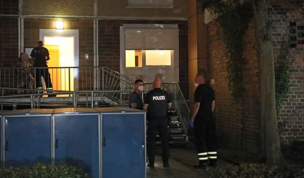 Beamte stehen vor der Wohnung des 25-Jährigen Rostockers, der am Samstagabend attackiert wurde.