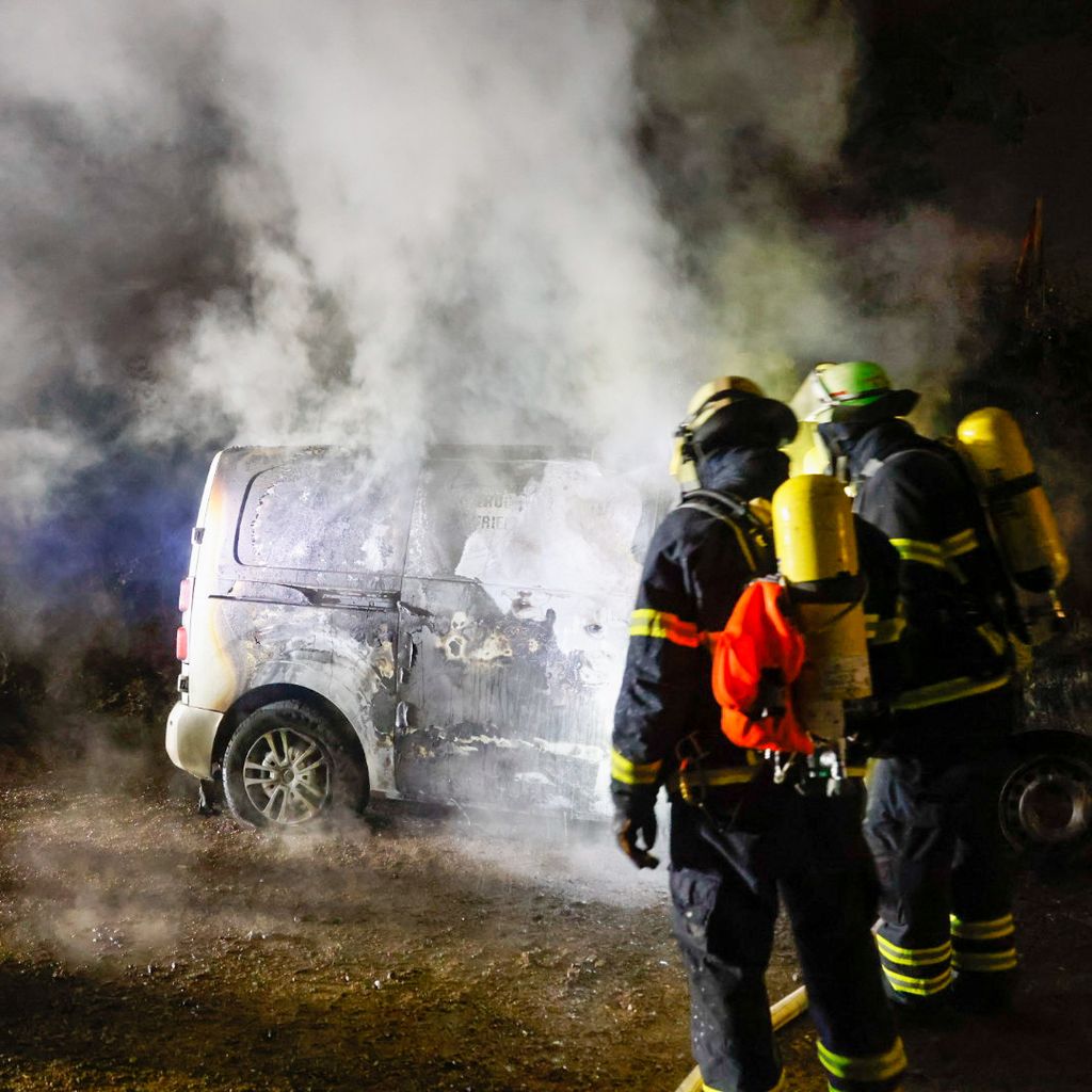 Feuerwehrleute vor einem der ausgebrannten Transporter in Bramfeld.