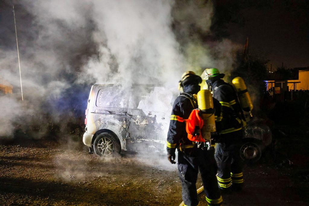 Feuerwehrleute vor einem der ausgebrannten Transporter in Bramfeld.