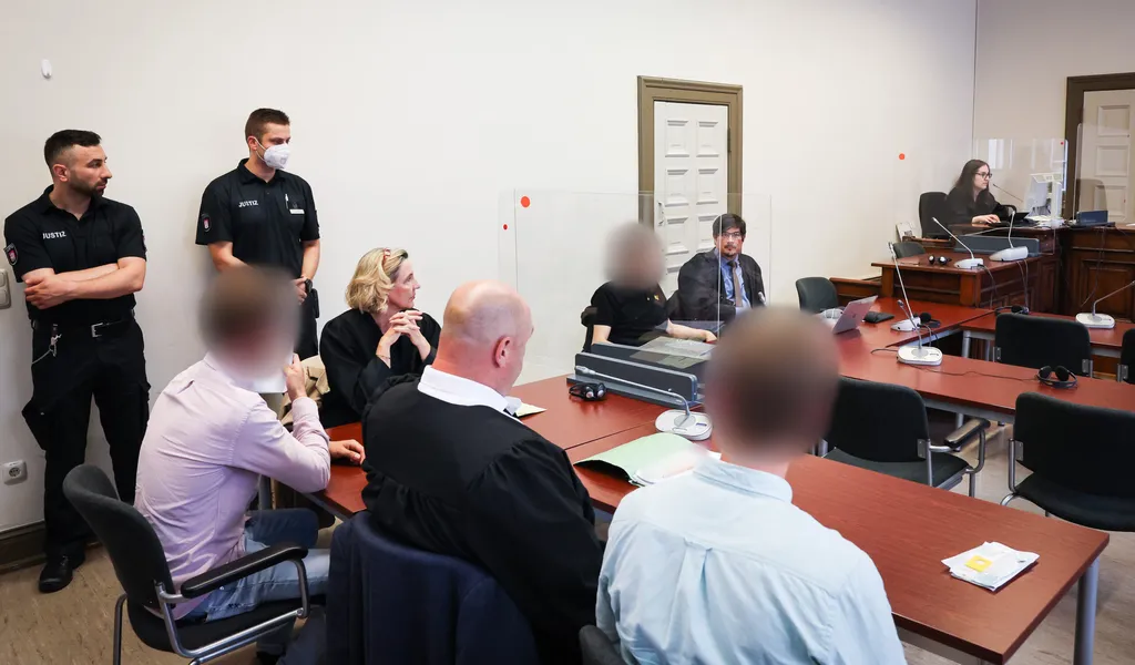 Der Hauptangeklagte (hinten), zwei weitere Angeklagte sowie weitere Beteiligte beim Prozess im Hamburger Strafjustizgebäude