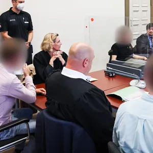 Der Hauptangeklagte (hinten), zwei weitere Angeklagte sowie weitere Beteiligte beim Prozess im Hamburger Strafjustizgebäude