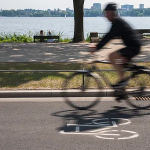Ein Fahrradfahrer radelt an der Alster entlang.
