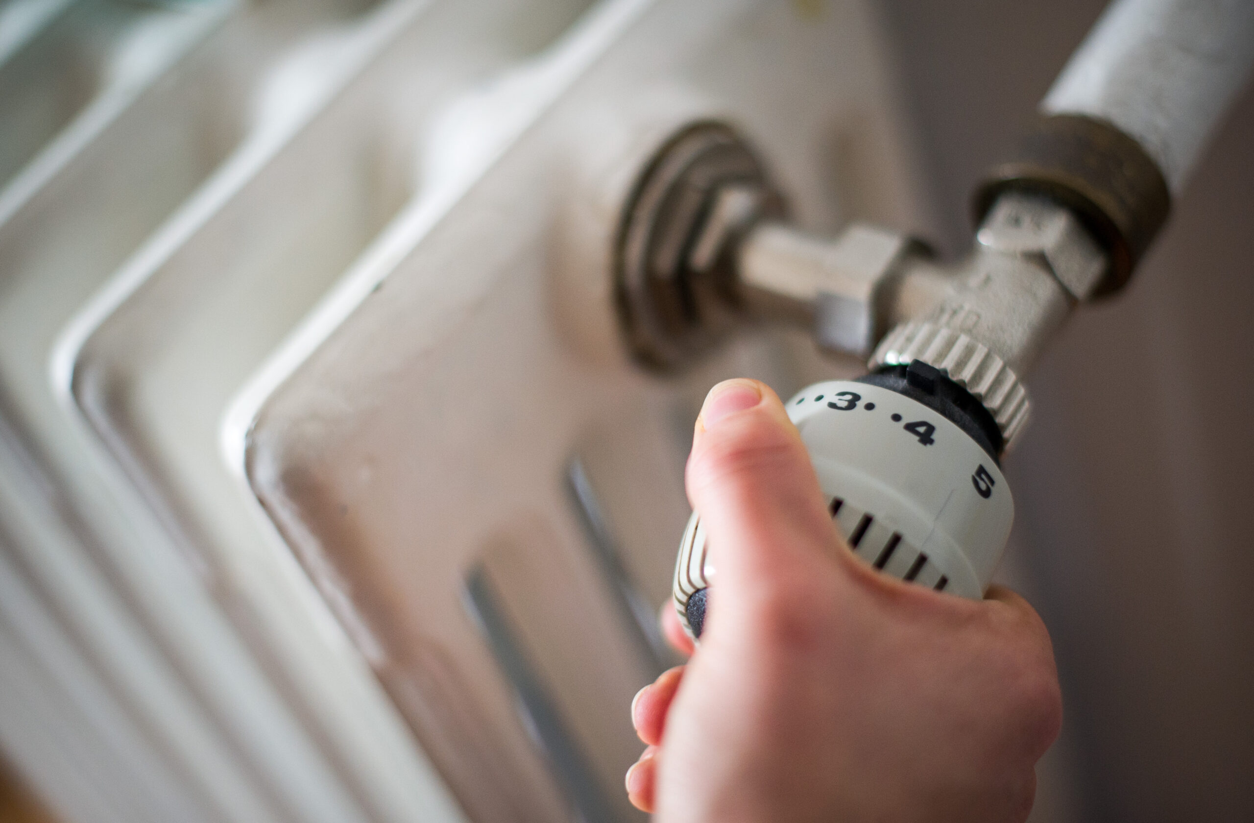 Eine Frau dreht am Thermostat einer Heizung. (Symbolbild)