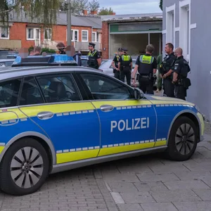 Ein Polizeiwagen und mehrere Einsatzkräfte vor einem Haus