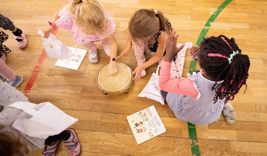 Drei Mädchen spielen in einem Kindergarten mit einem Musikinstrument.