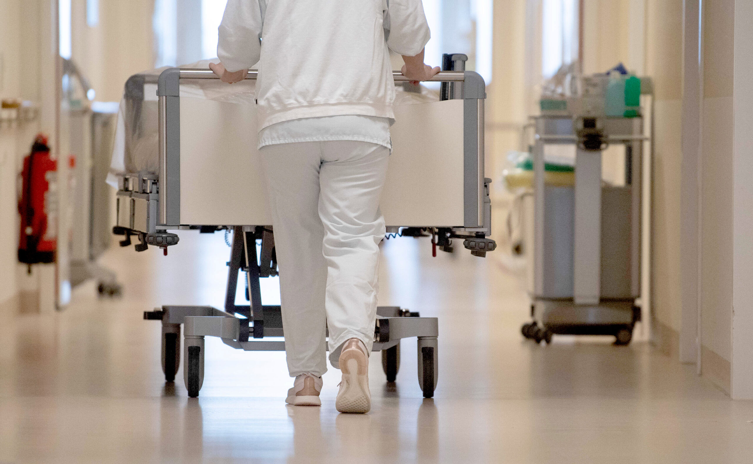 Pflegekraft schiebt ein Krankenbett durch den Krankenhausflur