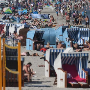 Touristen nutzen das hochsommerliche Wetter am Strand auf der Insel Rügen zum Sonnen und Baden.