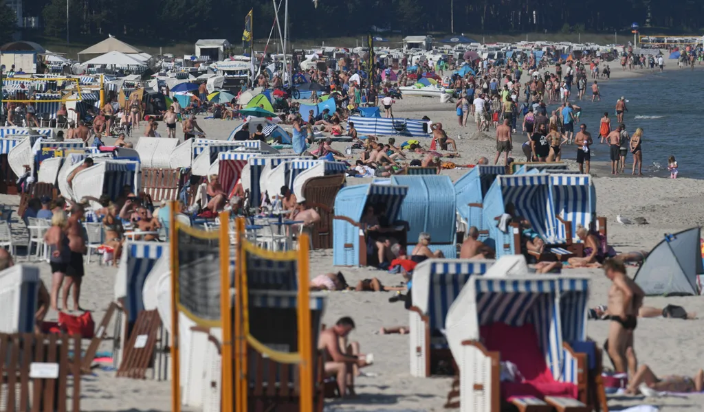 Touristen nutzen das hochsommerliche Wetter am Strand auf der Insel Rügen zum Sonnen und Baden.