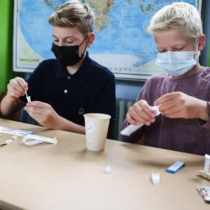 Schüler mit Maske führen einen Corona-Test durch.
