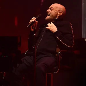 Der Musiker Phil Collins von der Band Genesis sitzt in der Mercedes-Benz Arena auf der Bühne.