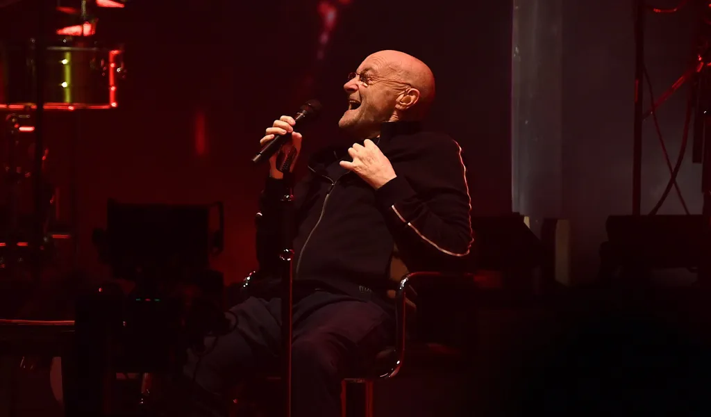 Der Musiker Phil Collins von der Band Genesis sitzt in der Mercedes-Benz Arena auf der Bühne.
