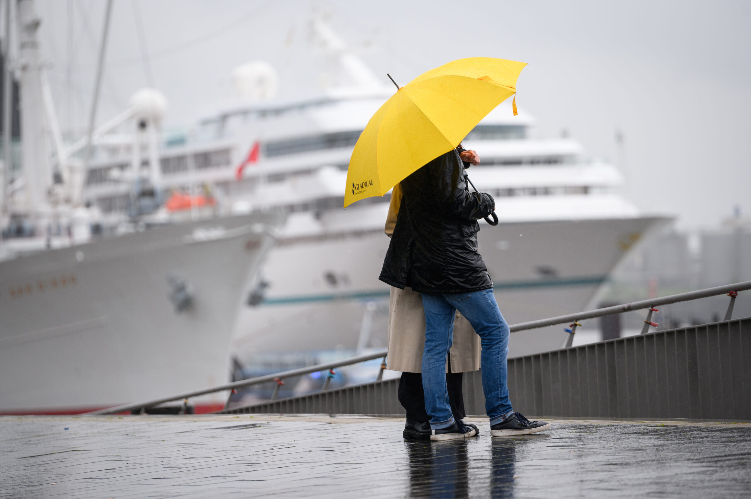 Ein Pärchen stehen unter einem Regenschirm auf der Jan-Fedder-Promenade einem Kreuzfahrtschiff