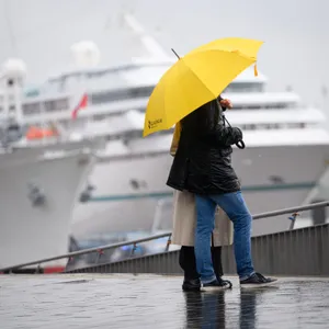 Ein Pärchen stehen unter einem Regenschirm auf der Jan-Fedder-Promenade einem Kreuzfahrtschiff