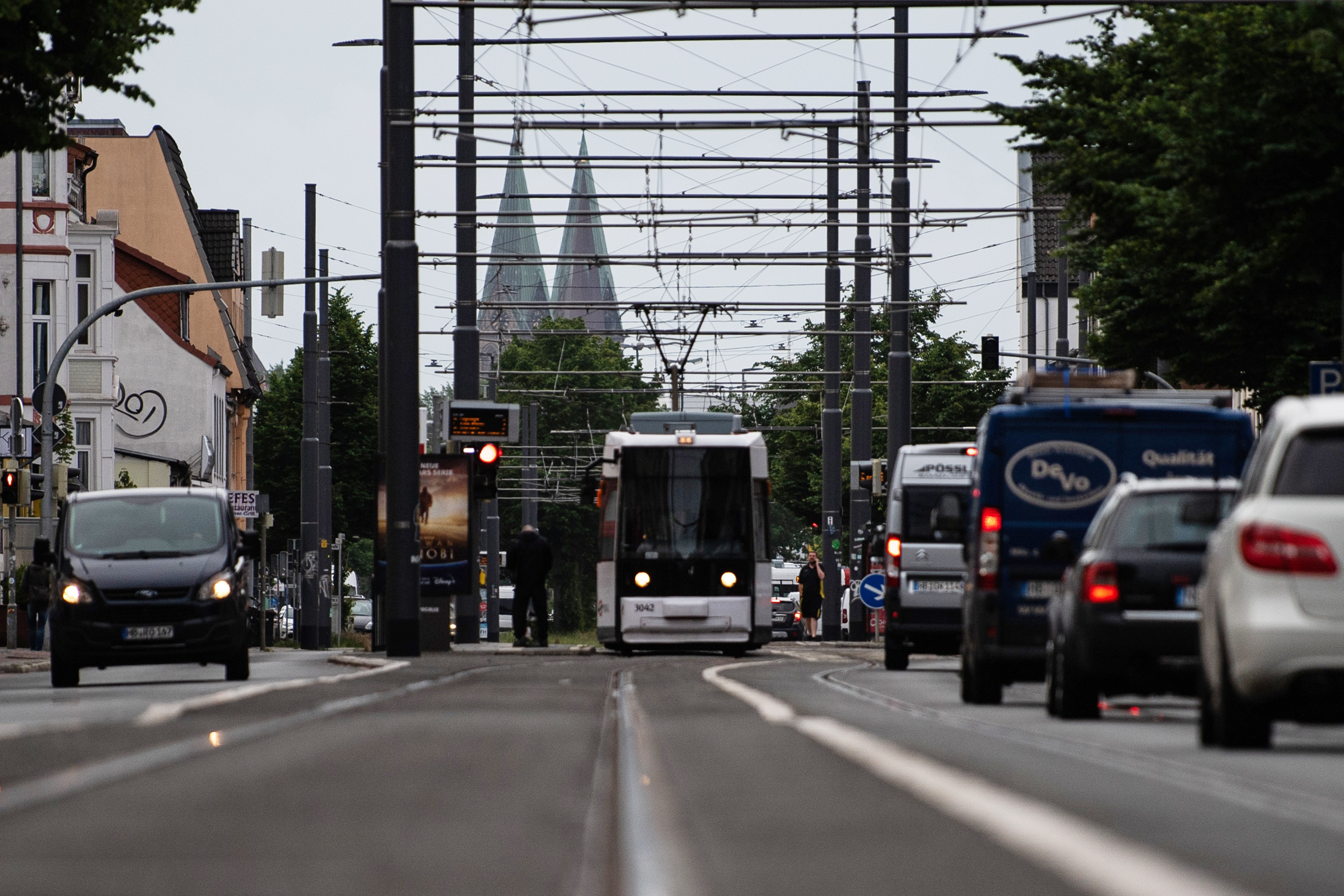 Eine Straßenbahn und Autos fahren morgens im Berufsverkehr durch die Stadt.