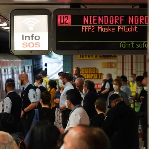 Menschen mit Masken auf Bahnsteig