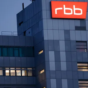Das beleuchtete Logo des Senders Rundfunk Berlin-Brandenburg (RBB) ist an der Fassade am Sitz des Senders an der Masurenallee angebracht.